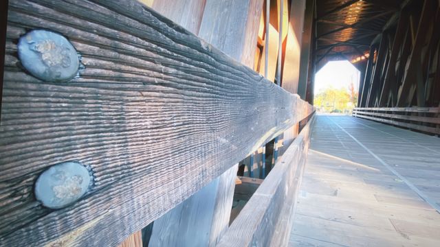 Weathered rail of a covered bridge, looking through to the light