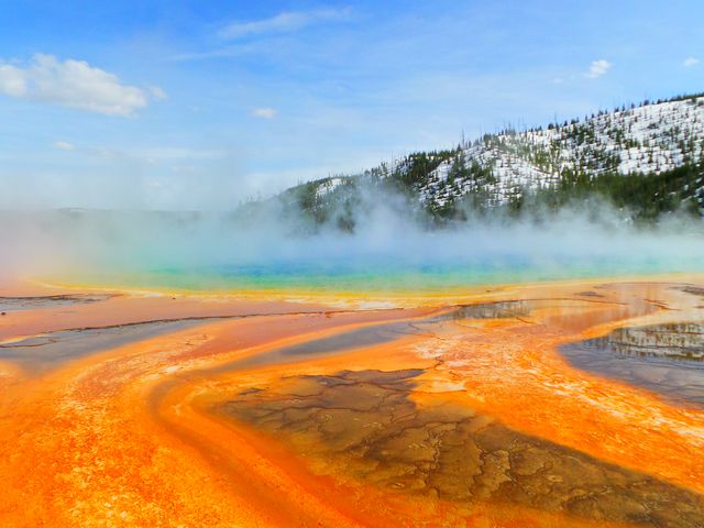 Steam rising off the orange and blue terraces of Grand Prismatic Spring